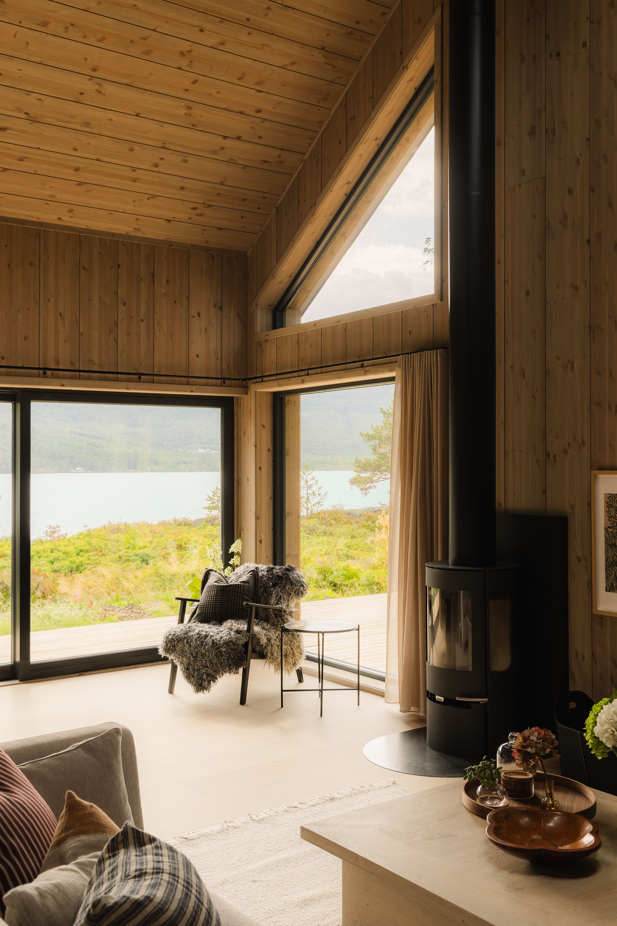 Woonkamer met houtkachel en panoramisch uitzicht op het meer