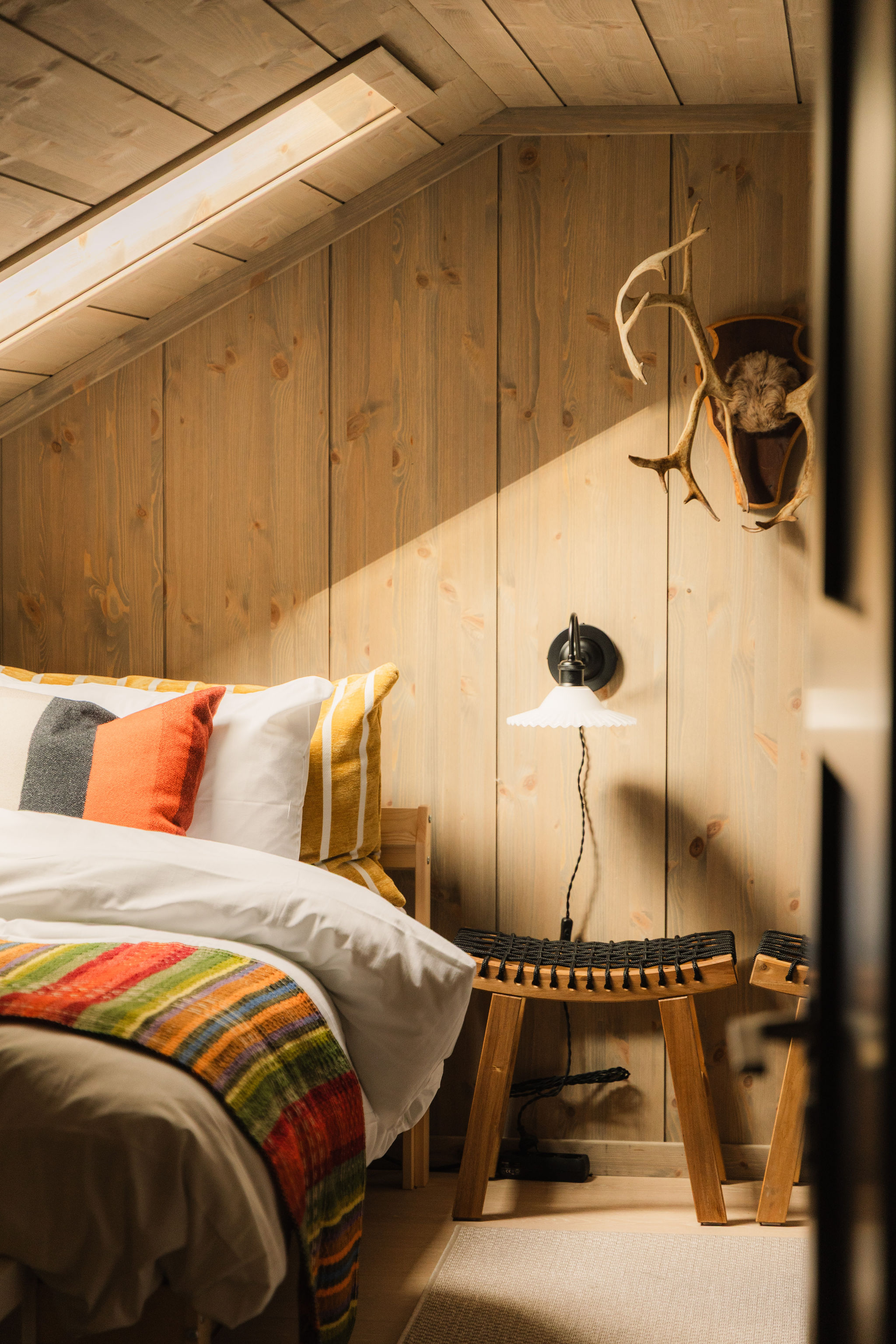Slaapkamer onder het schuine dak met kleurrijke plaid en gewei