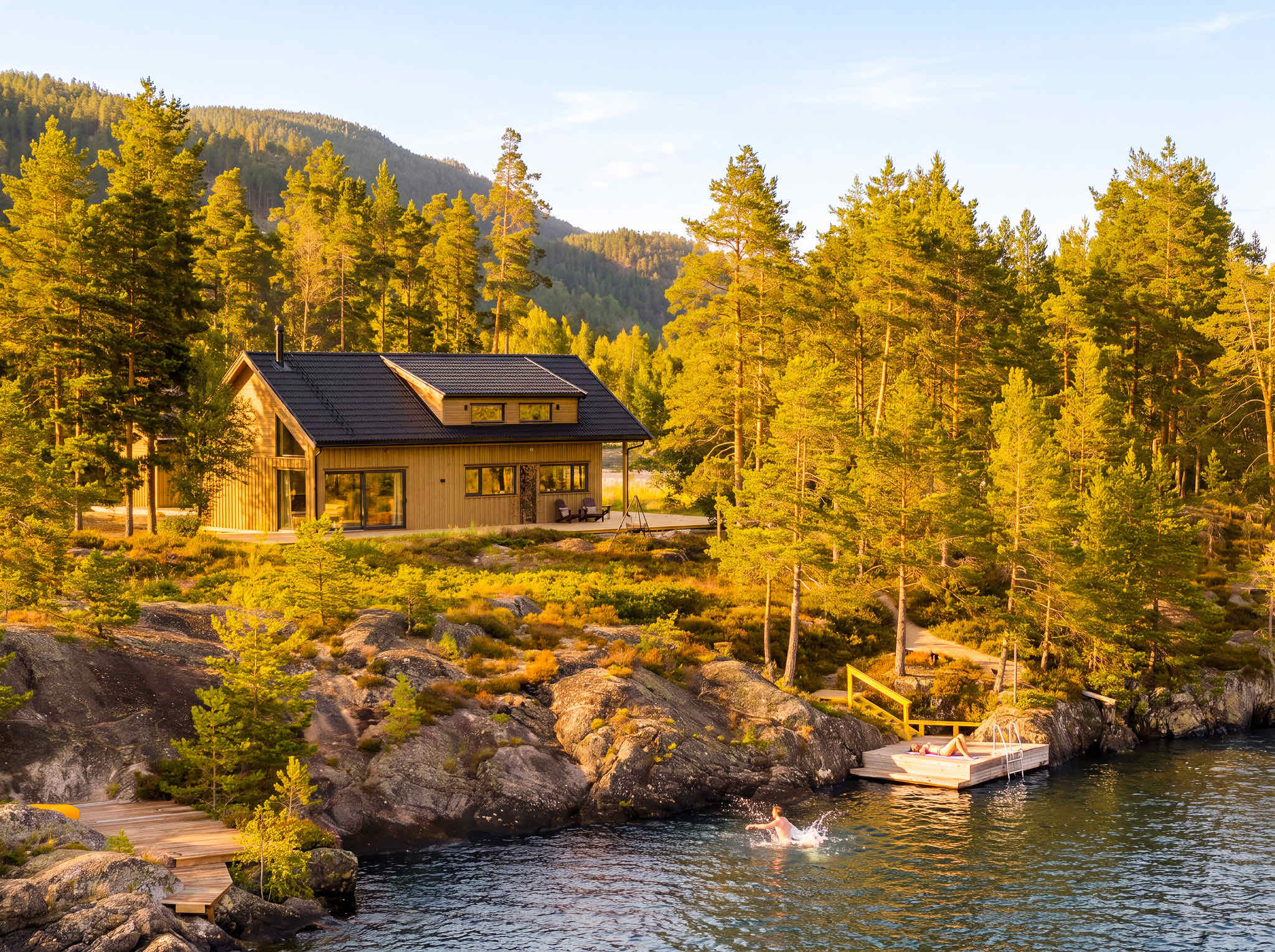 Lake House Sundsøy aan het meer, met zwemmers bij de eigen steiger in het gouden avondlicht